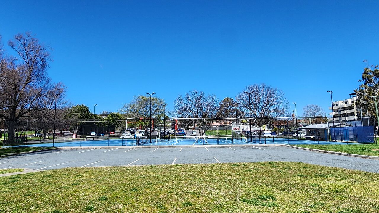 A park with tennis and pickleball courts under a blue sky