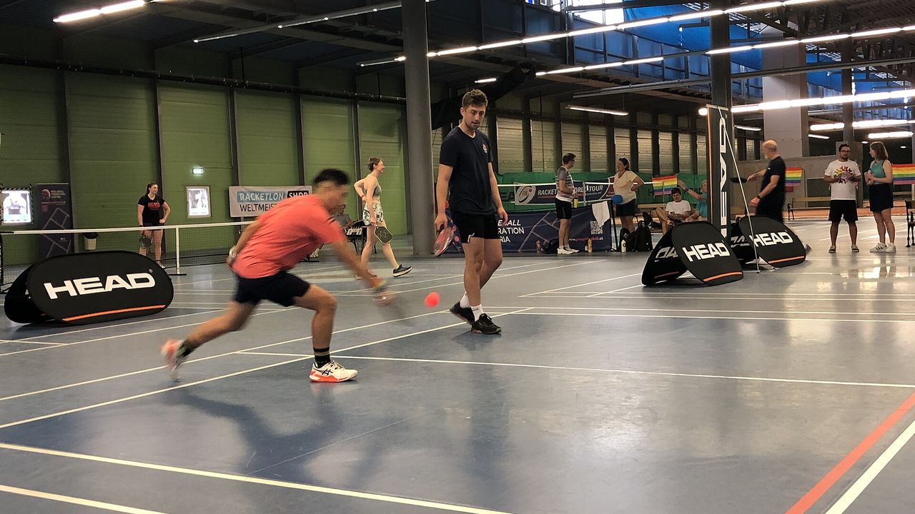 A player lunging for the ball at an indoor pickleball tournament