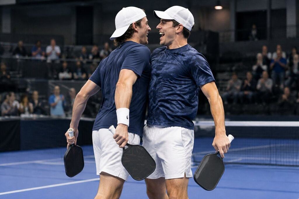 Two male pickleball players chest-bumping in celebration after winning a doubles final indoors
