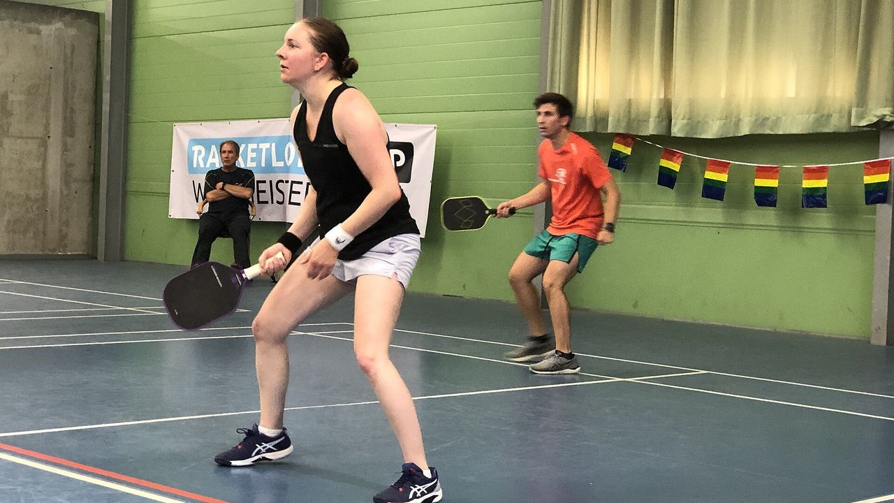 A player ready at the net at an indoor pickleball tournament