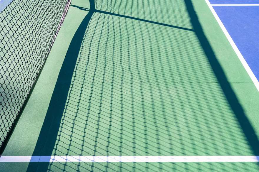 Pickleball net casting a long shadow across an empty court