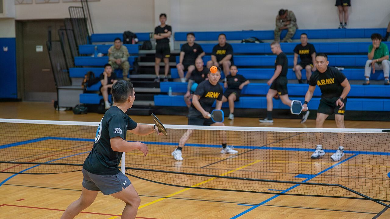 Players at the net during a gym pickleball game
