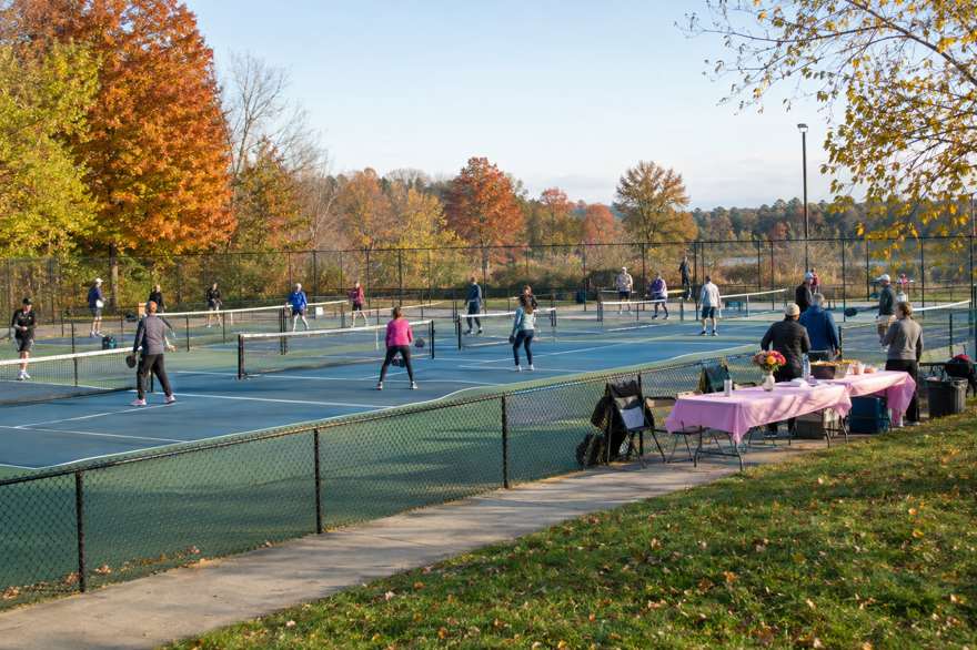 Illustrative image of a community pickleball tournament on outdoor courts on an autumn morning