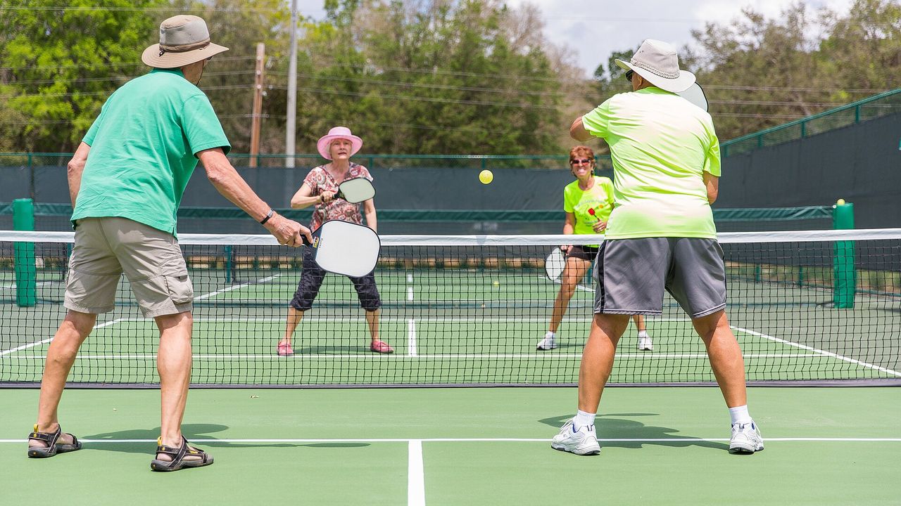 Four players in a doubles pickleball game on an outdoor court