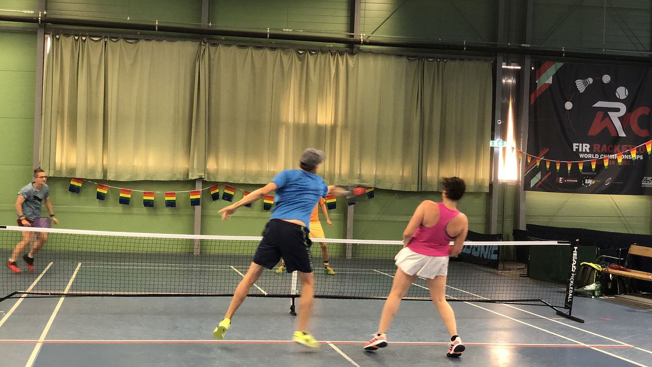 Two doubles players moving on an indoor pickleball court at a tournament