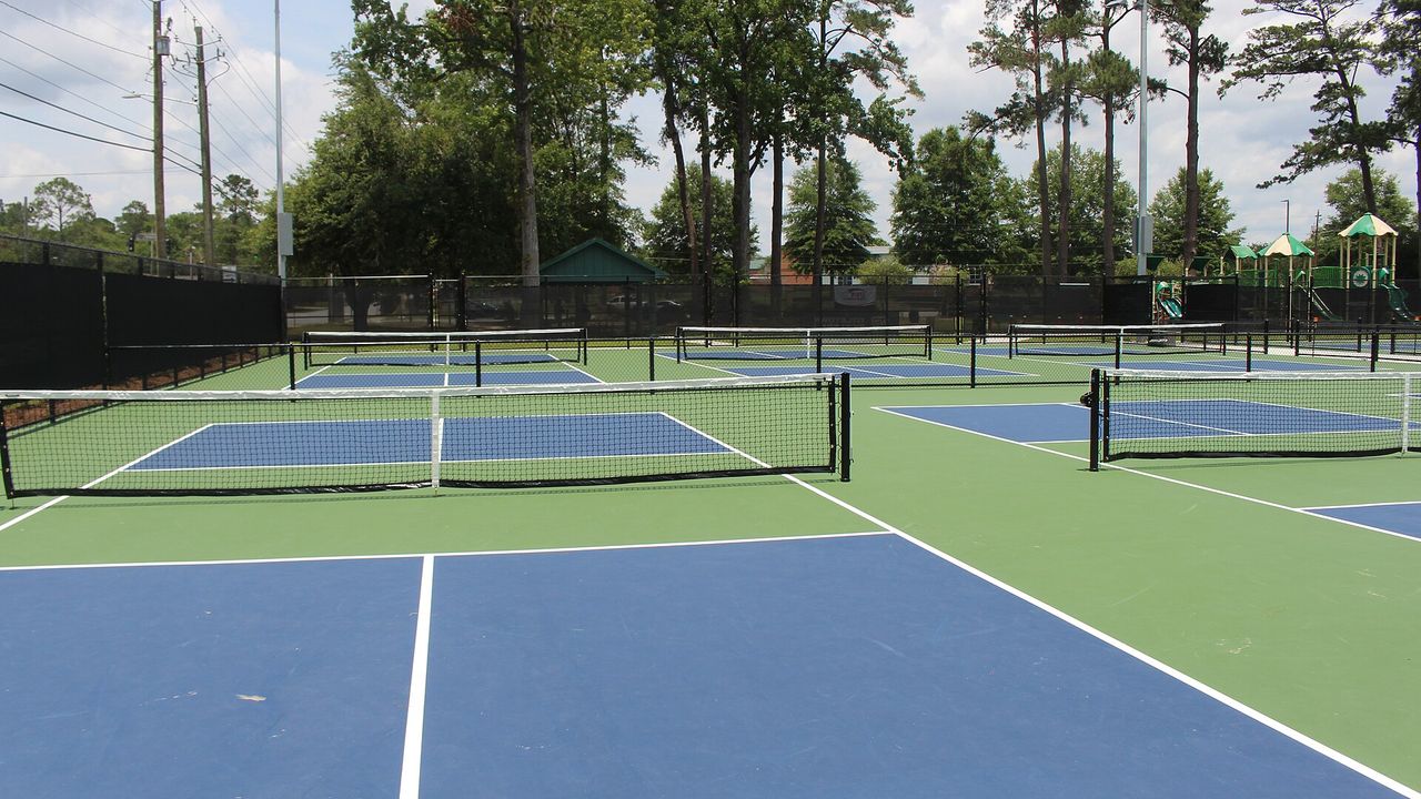 Pickleball courts surrounded by tall pine trees