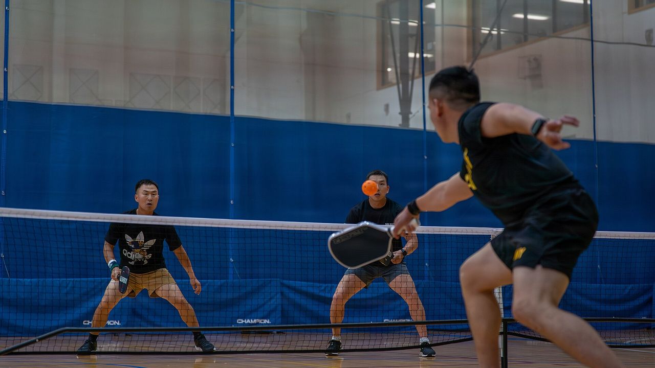 Two players ready at the net during an indoor pickleball game