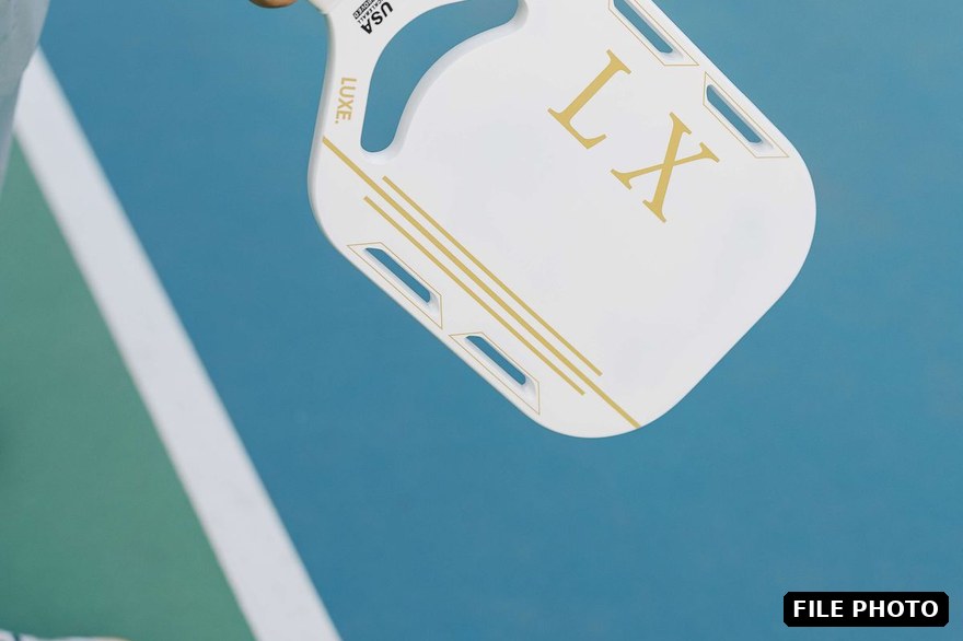 Pickleball paddle held over an outdoor court