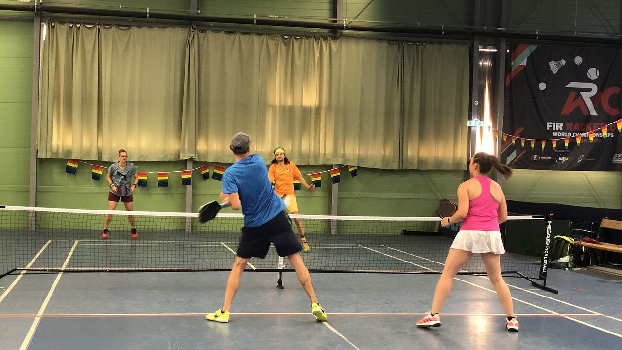 Two players in a mixed doubles pickleball match indoors
