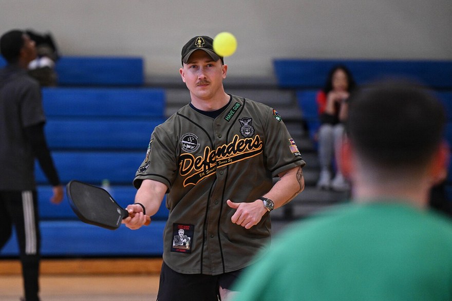 A player tossing a ball up to serve during a recreational indoor match