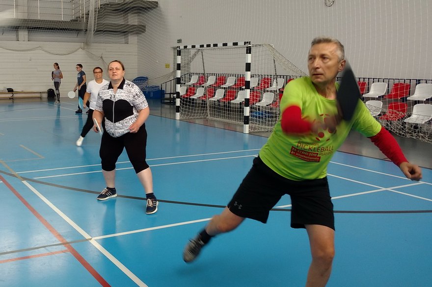 Players practicing pickleball indoors in a multi-sport hall