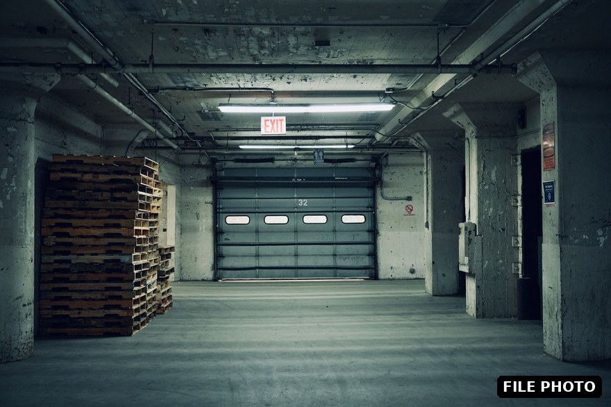 An empty industrial warehouse interior with concrete pillars and a loading door