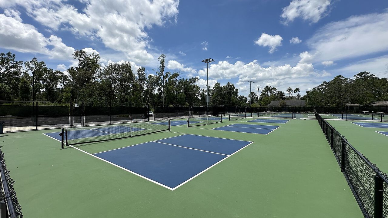 Pickleball courts with a blue playing surface and green surround