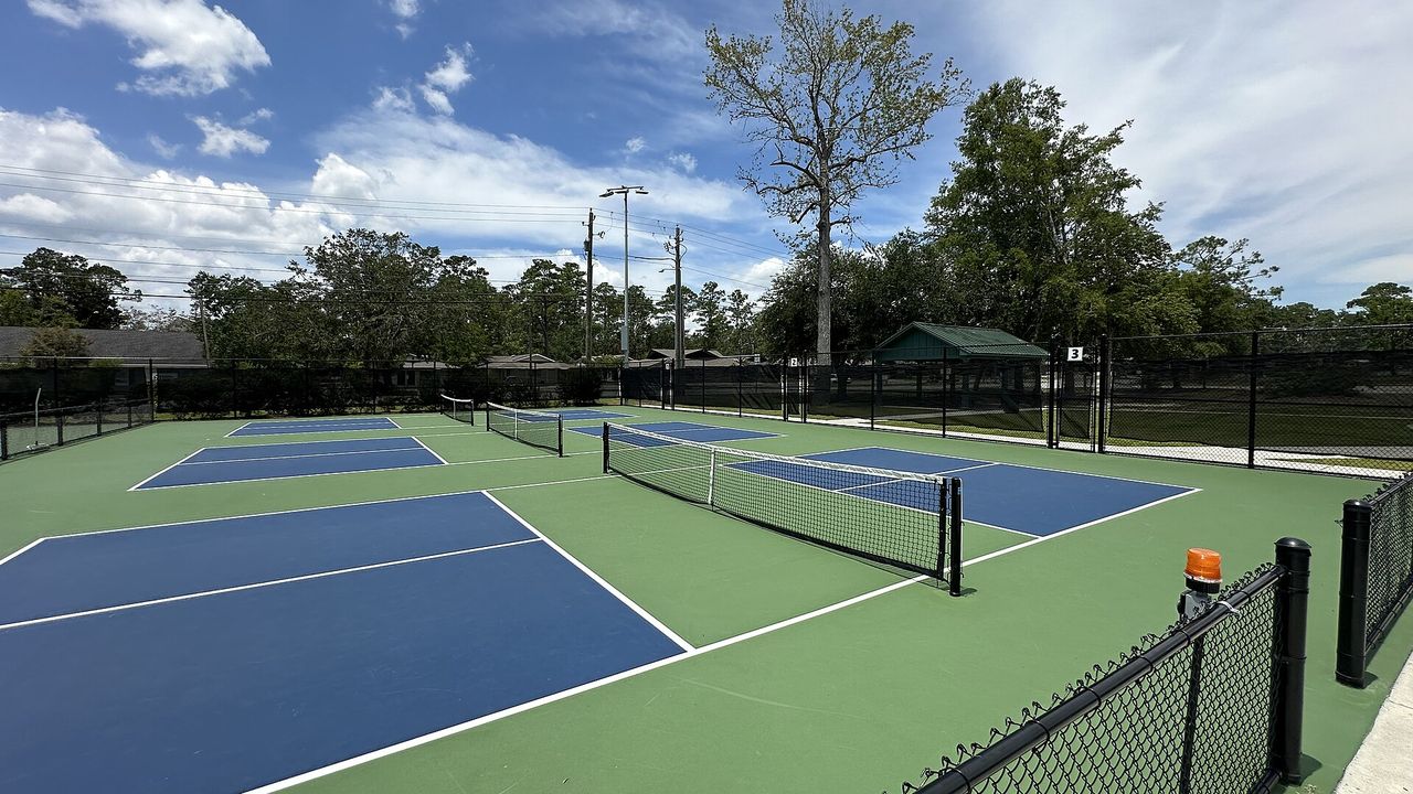 Pickleball courts with a blue playing surface and green surround
