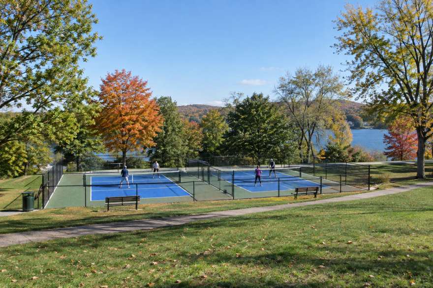 Illustrative image of two outdoor pickleball courts in a lakeside park in autumn