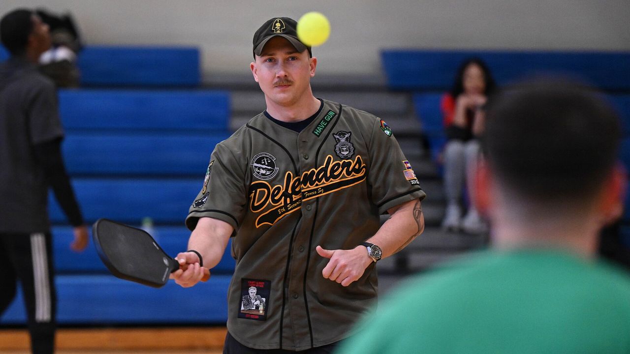 A player holding a paddle during a pickleball game in a gym