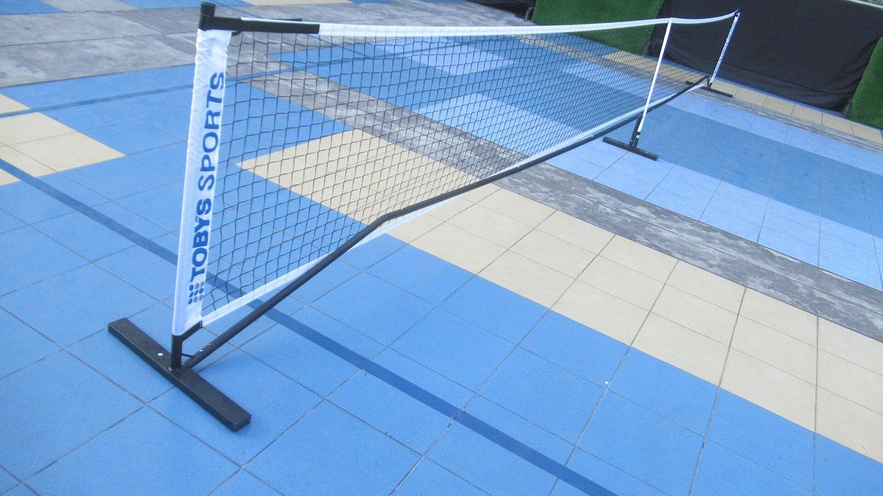 A portable pickleball net on a blue court surface