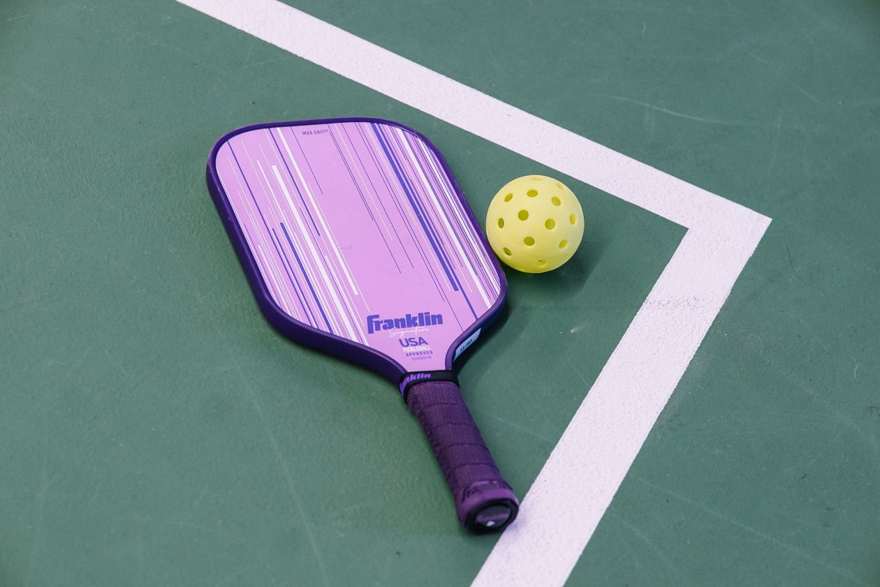 A pickleball paddle and ball on a court corner