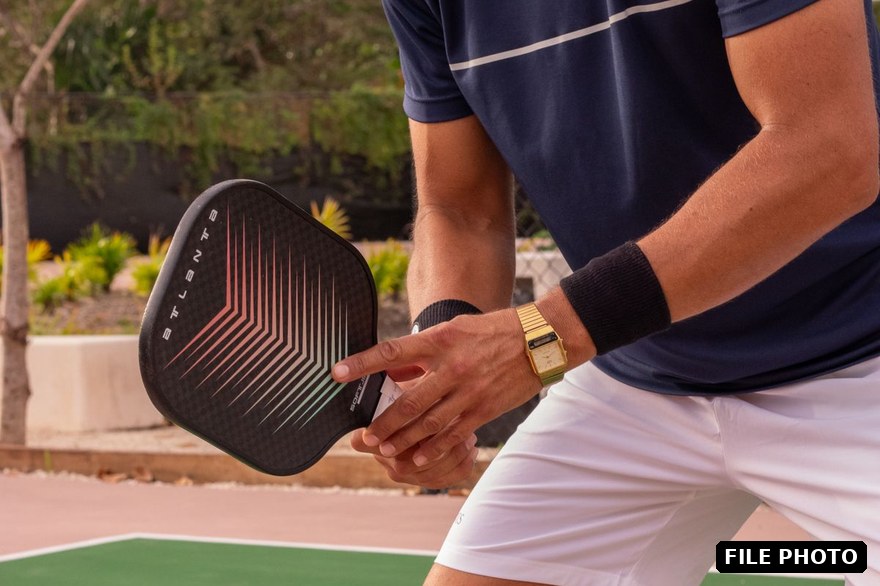 Player holding a pickleball paddle on an outdoor court
