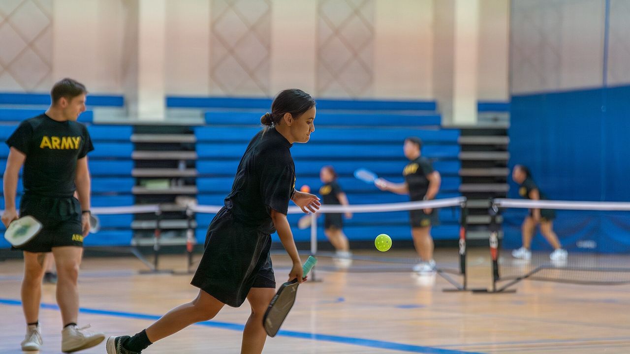 Two players at the net during an indoor pickleball match