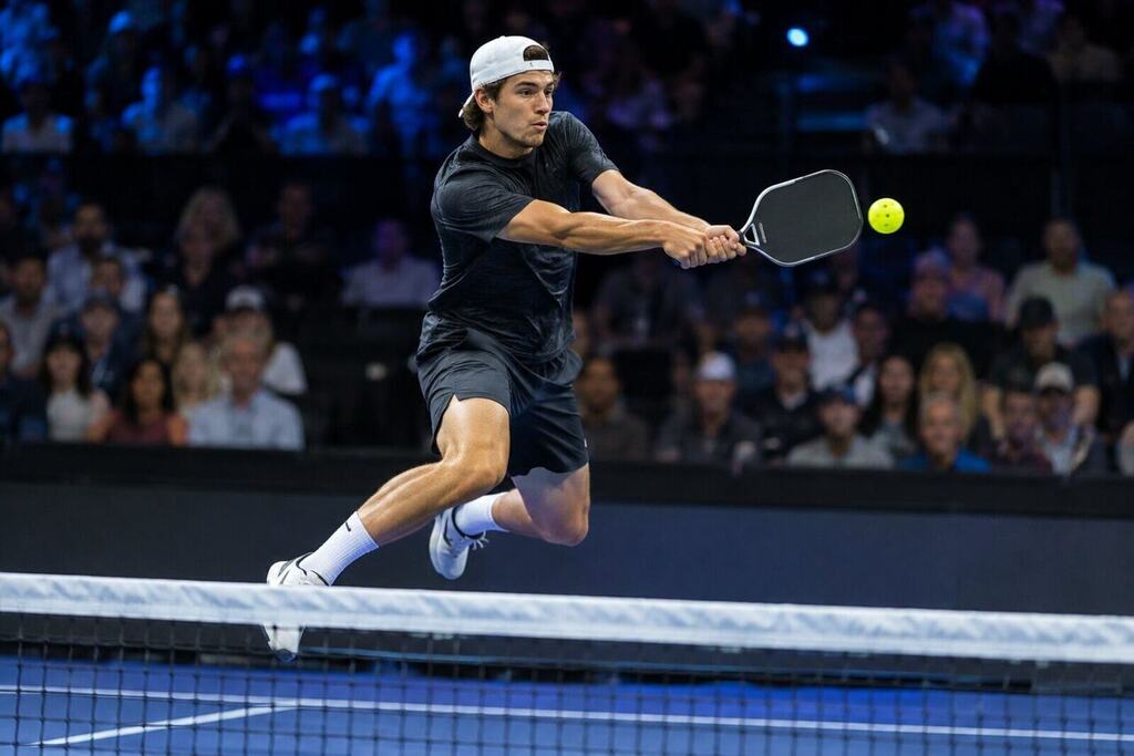 A young male pickleball player hitting a backhand Erne at the kitchen line during a pro match