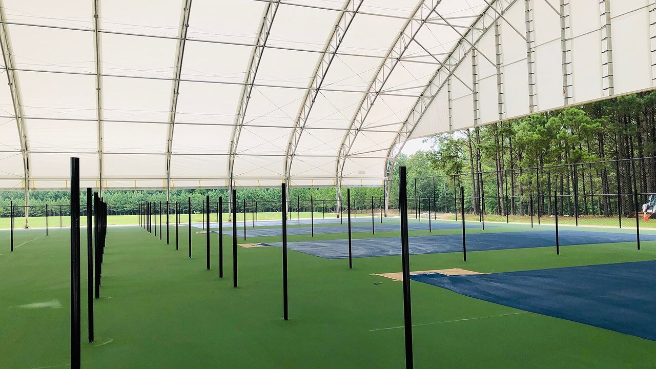 Pickleball courts under a large covered roof with open sides
