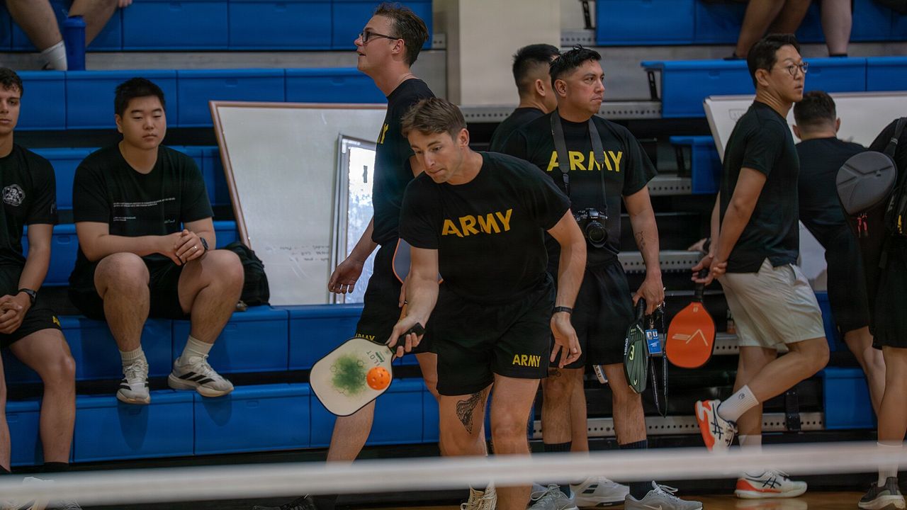 Players waiting courtside during a pickleball tournament in a gym
