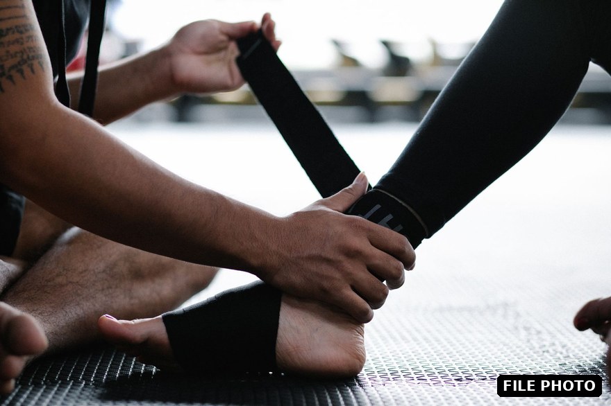 A person having their ankle wrapped with a black support bandage indoors