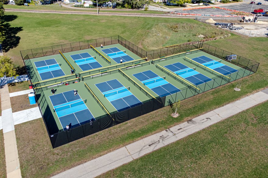 Aerial view of six outdoor pickleball courts with players during open play in La Crosse, Wisconsin